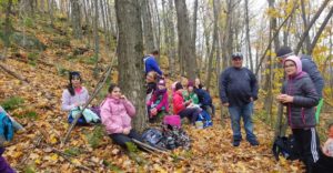 Une dizaine de jeunes filles louvettes, âgées de 9 à 11 ans, se reposant sur un tapis de feuilles mortes
