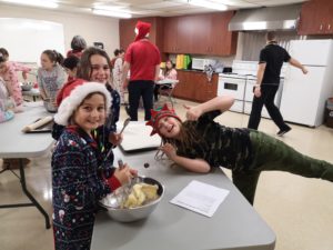 Une grande salle cuisine avec plusieurs jeunes filles cuisinant des biscuits aux pépites de chocolat