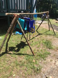 7 branches assemblées pour fabriquer une corde à linge, avec des vestes de sauvetage séchant sur la corde.