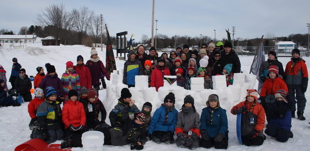 Une photo de groupe avec tous les membres du 10ème Est-Calade, devant un château de neige, construit sur le terrain de l'école Desranleau, en hiver 2018.